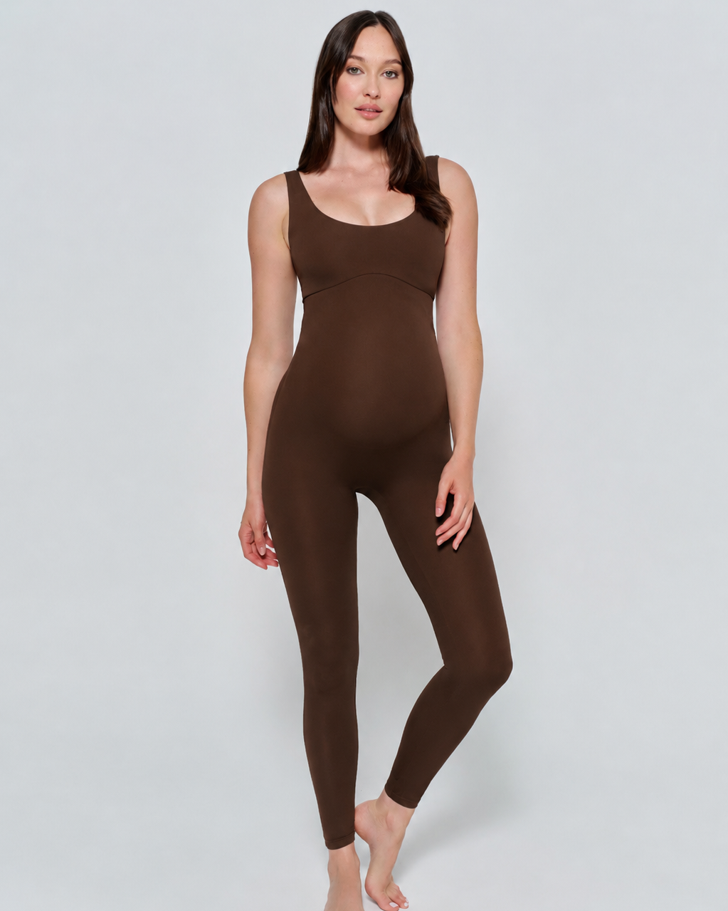 Woman wearing a chocolate brown Bumpsuit bodysuit on a light gray background