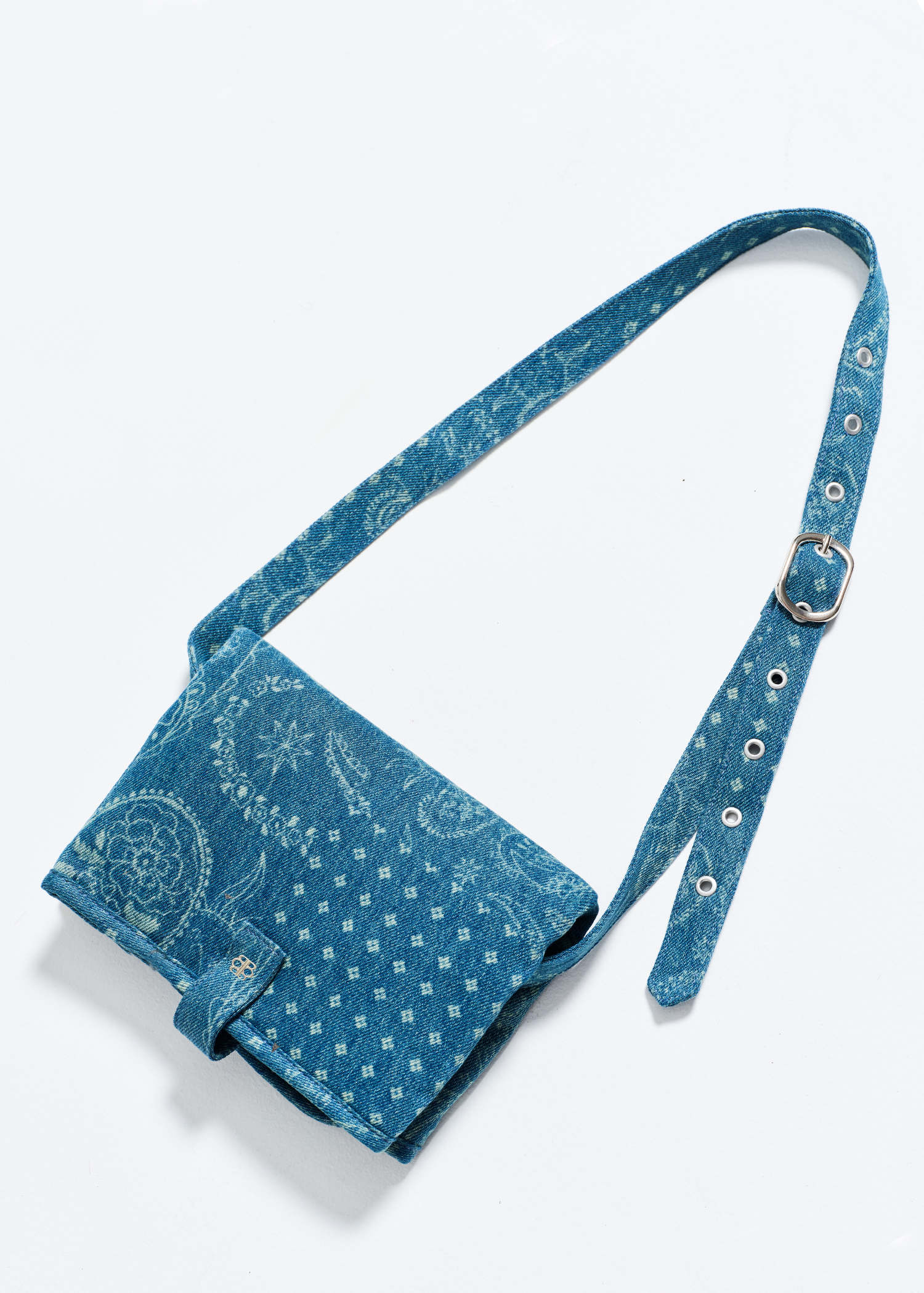 Blue denim crossbody changing mat bag with pattern on a white background
