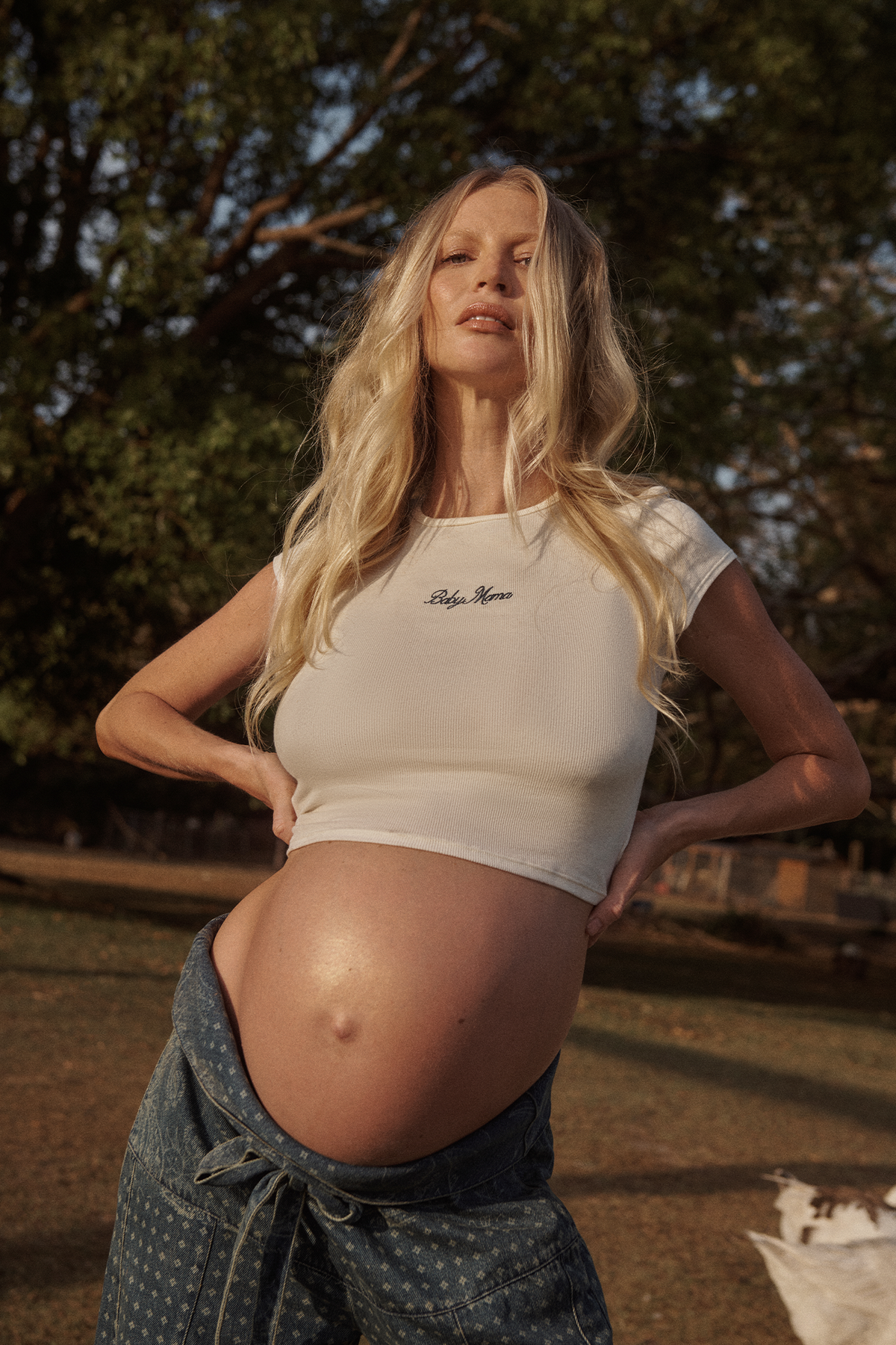 Pregnant woman wearing a white Bumpsuit baby mama tee