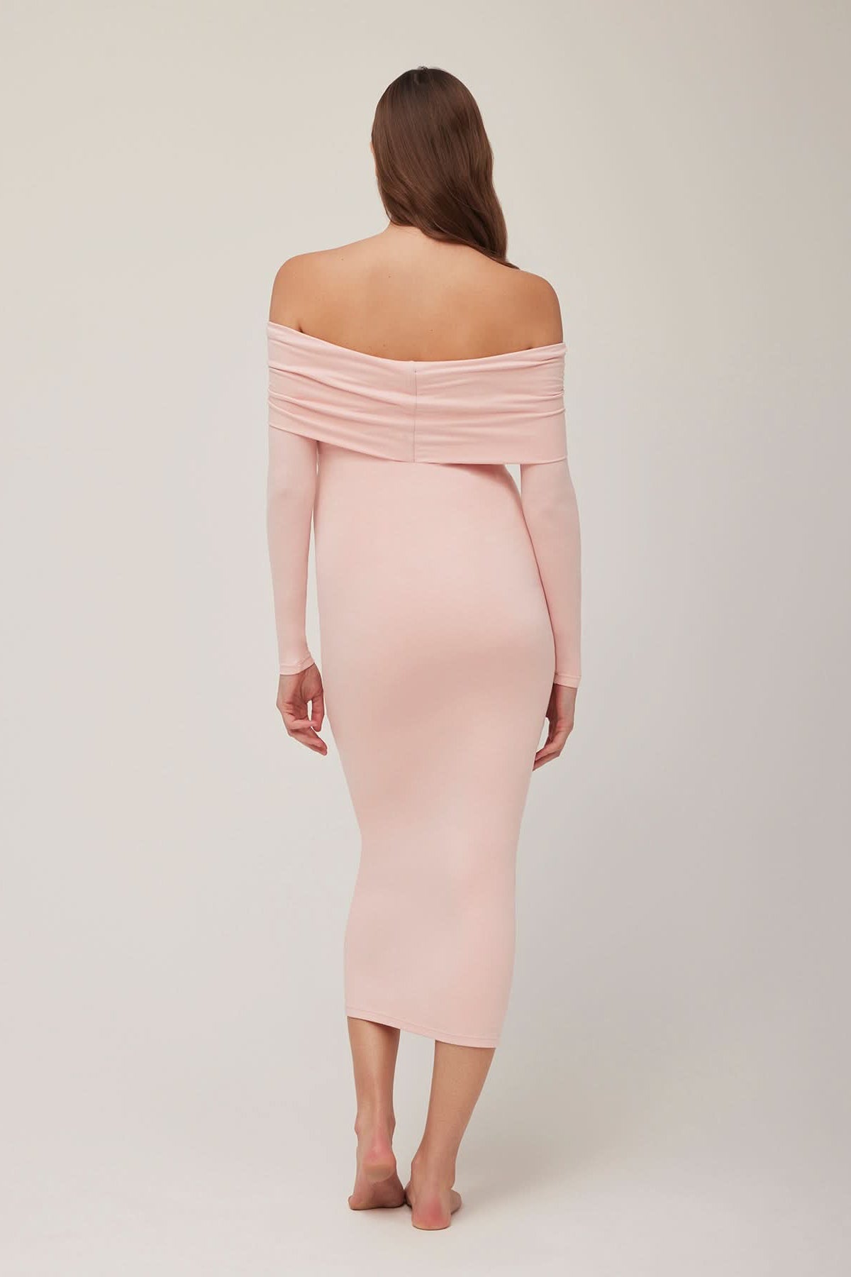 Back view of a pregnant woman wearing a dusty pink off-shoulder dress