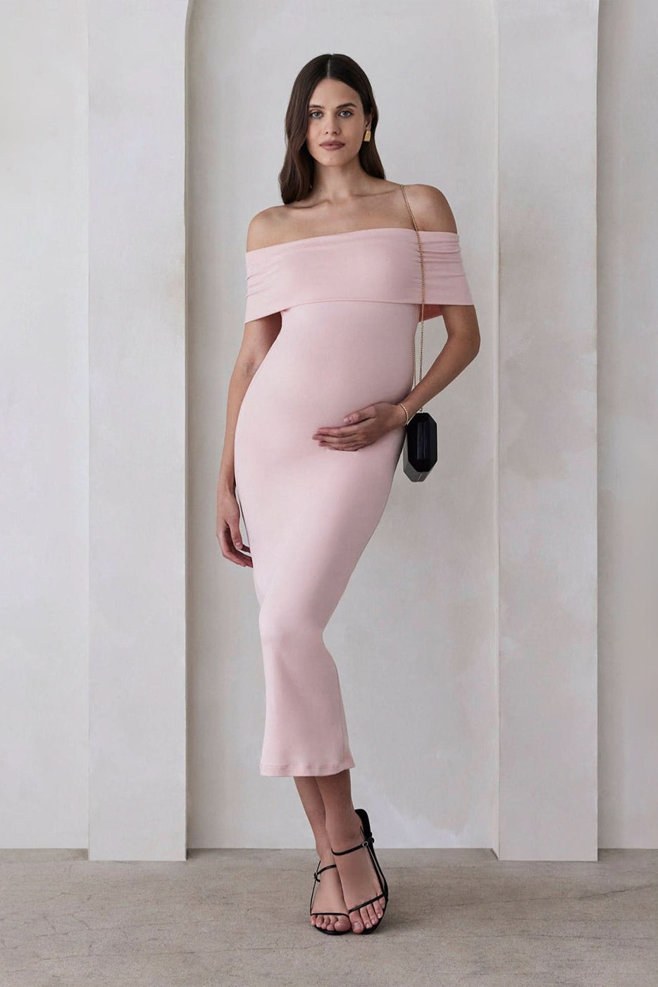 Pregnant woman wearing the Bumpsuit Maternity The Bianca Off Shoulder Maxi Dress in Dusty Pink