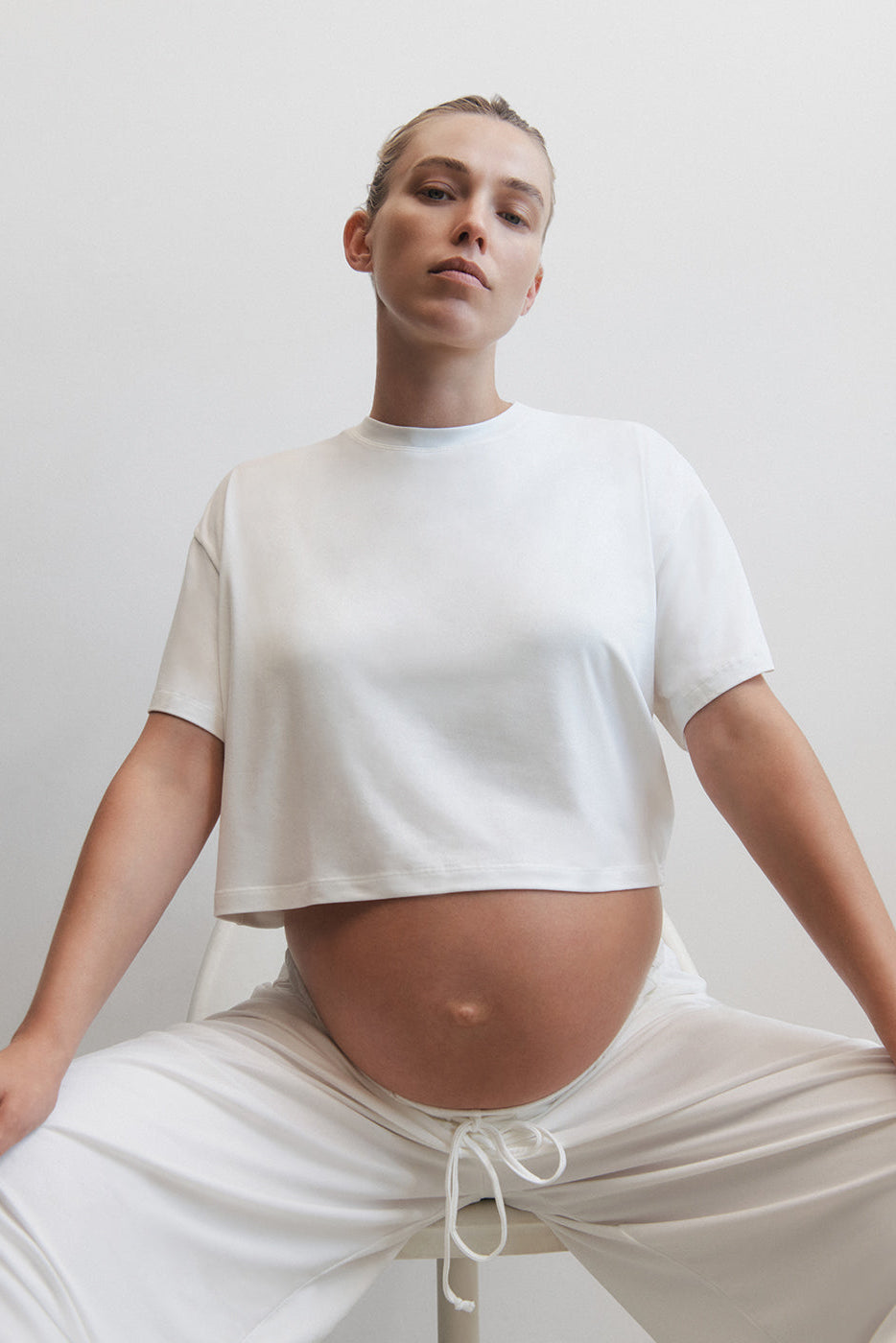 Pregnant woman wearing the cloud maternity crop tee in ivory