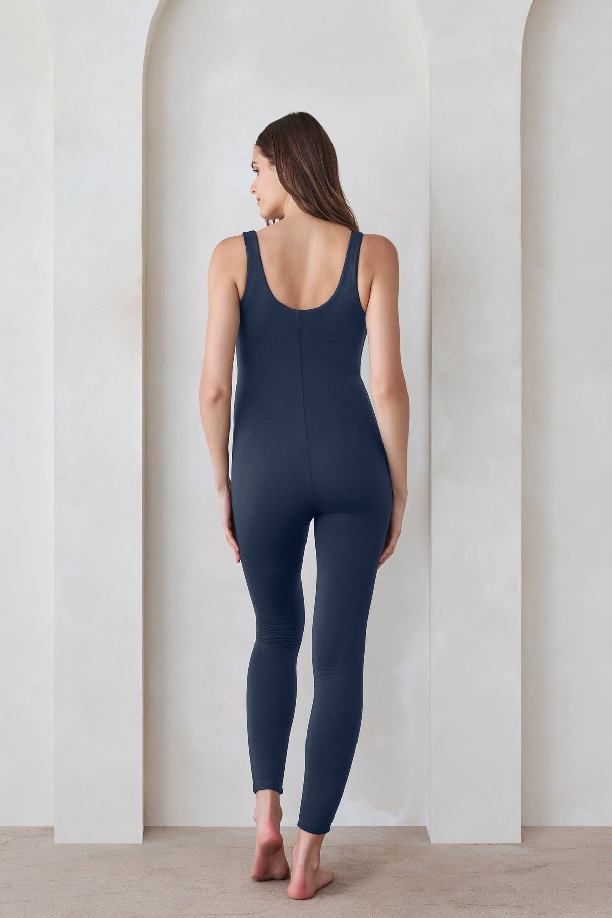 Back view of a pregnant woman in a navy jumpsuit by Bumpsuit