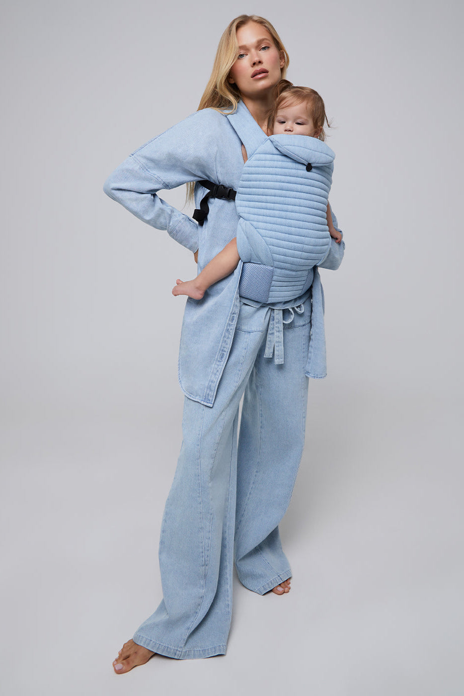 Front view of the light blue Denim Painter Jean showing its oversized wide-leg fit on a model with a baby carrier