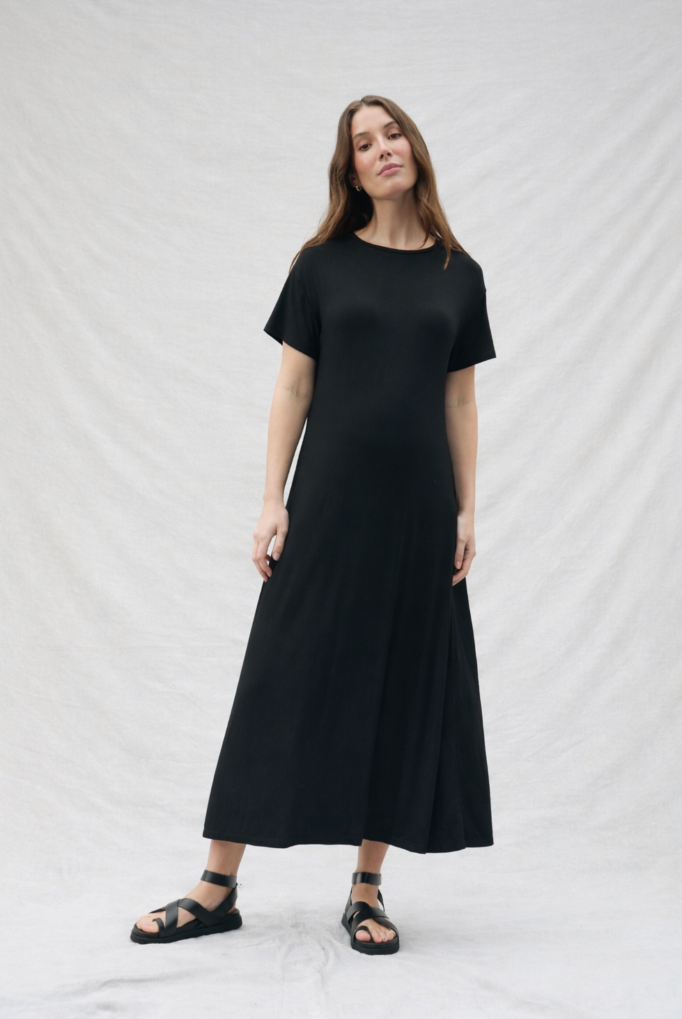 Pregnant woman wearing a black dress against a white background