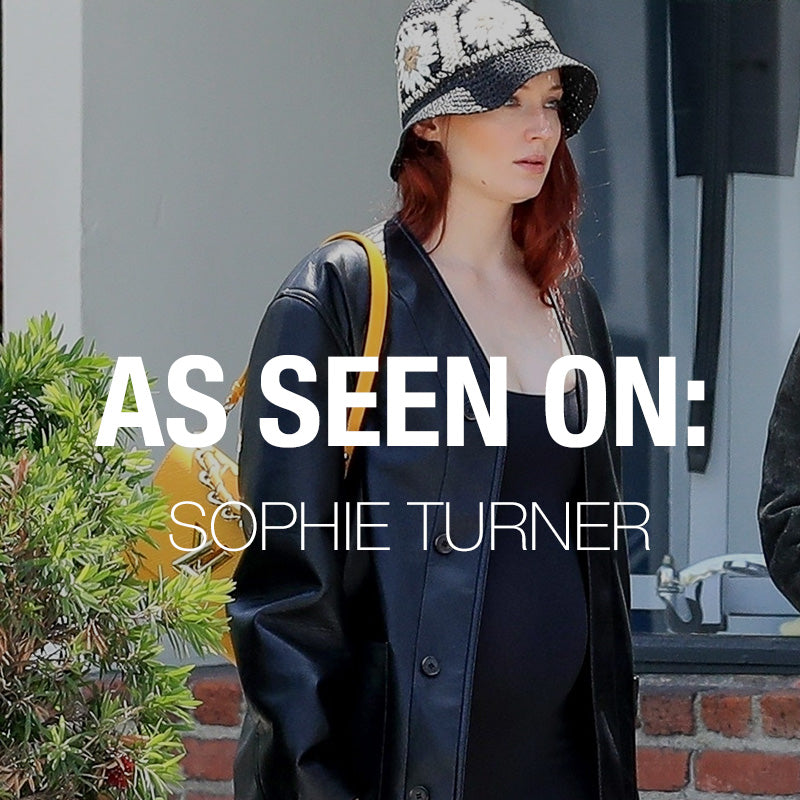 Sophie Turner in The Kate Original Bumpsuit and leather jacket, with overlay text As Seen On Sophie Turner