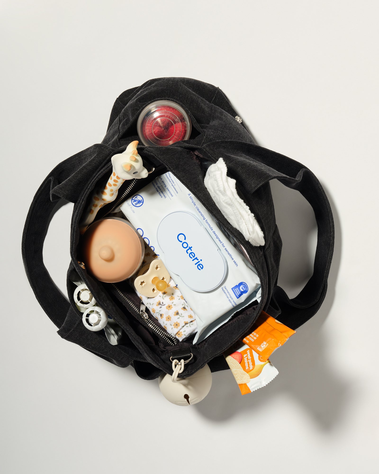 A black diaper bag shown from above, open to reveal baby essentials inside