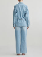 Person wearing a light blue denim outfit on a plain background