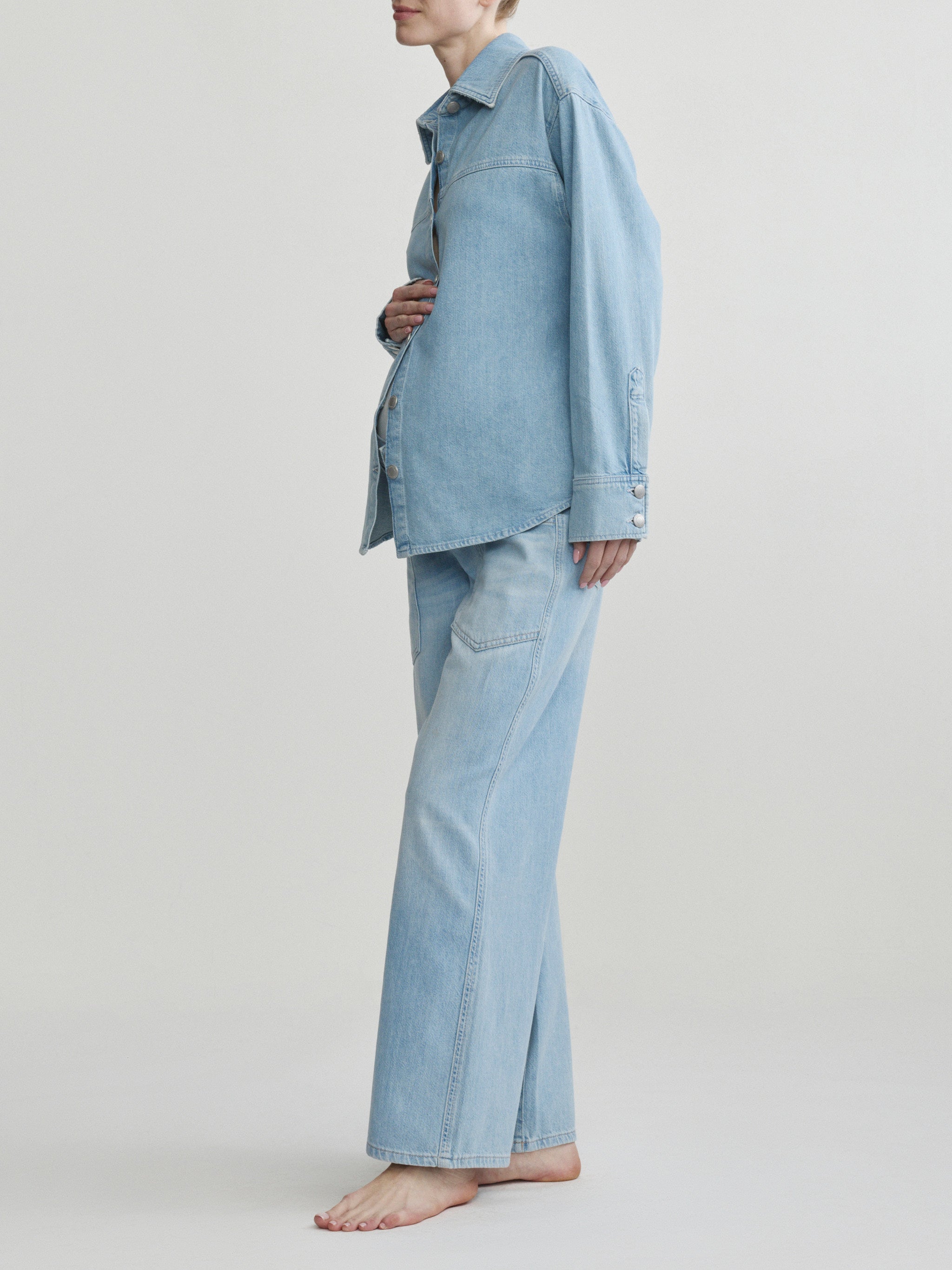 Person wearing a light blue denim outfit on a plain background