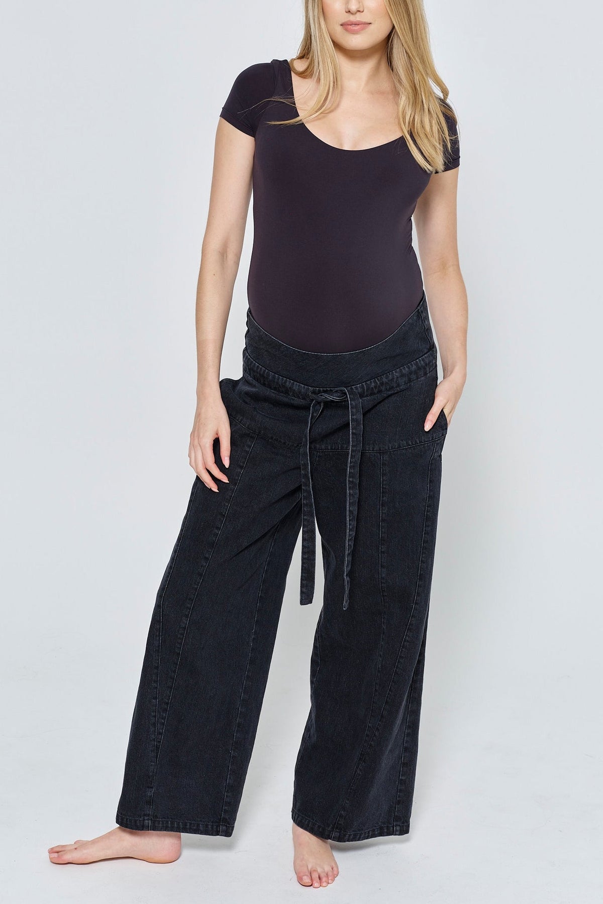 Front view of The Relaxed Denim Jean showcasing wide legs and drawstring waistband on a pregnant model in a studio