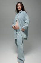 Pregnant women wearing a Bumpsuit denim jeans and denim shirt against a grey background