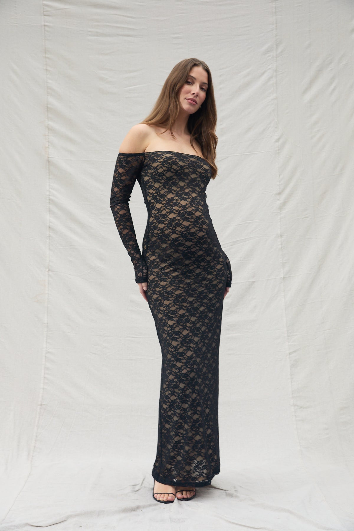 Pregnant woman in a black laced off the shoulder maxi dress 
