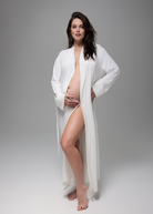 Woman wearing a bumpsuit white robe on a gray background