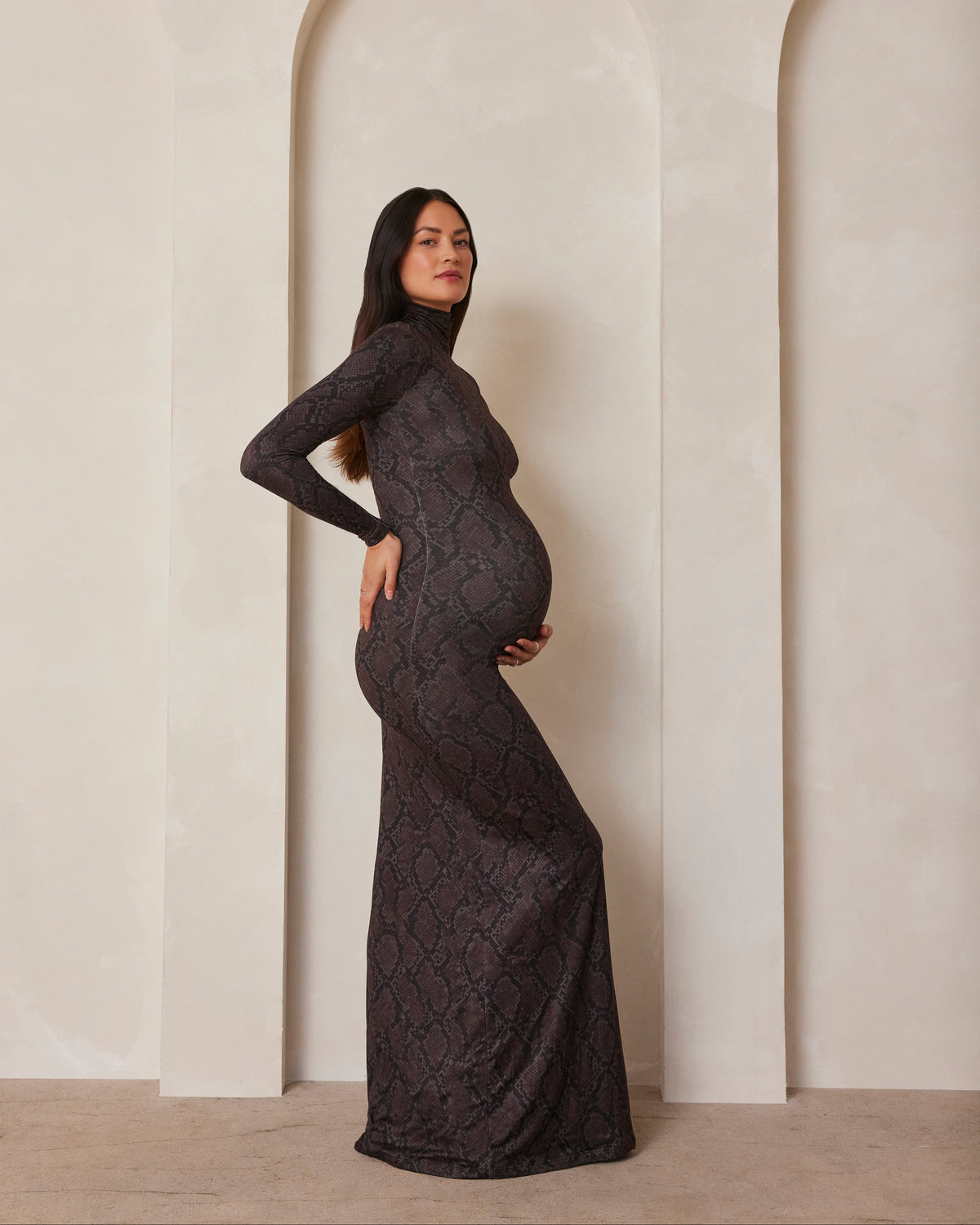 Pregnant model wearing a turtleneck long sleeve maxi dress in a snake print
