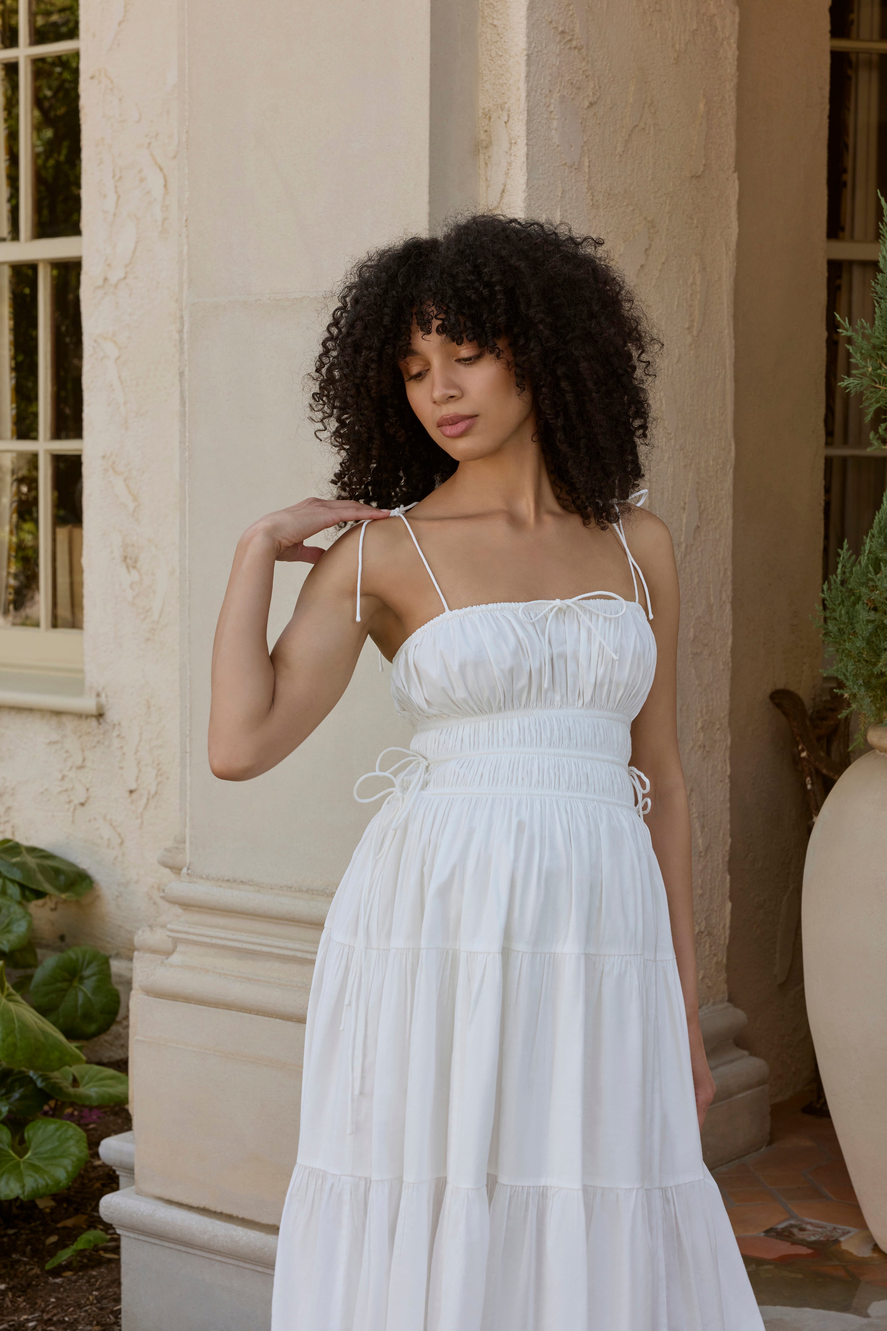 Woman in a white dress standing outdoors near a building