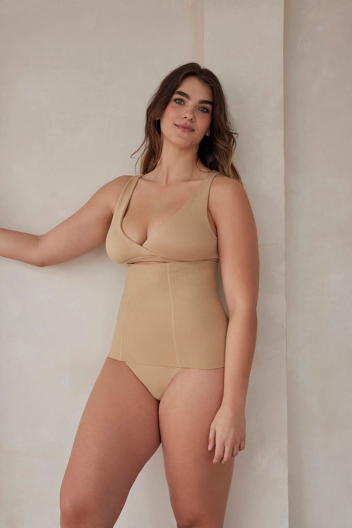 Woman wearing the postpartum support waist trainer in beige by bumpsuit