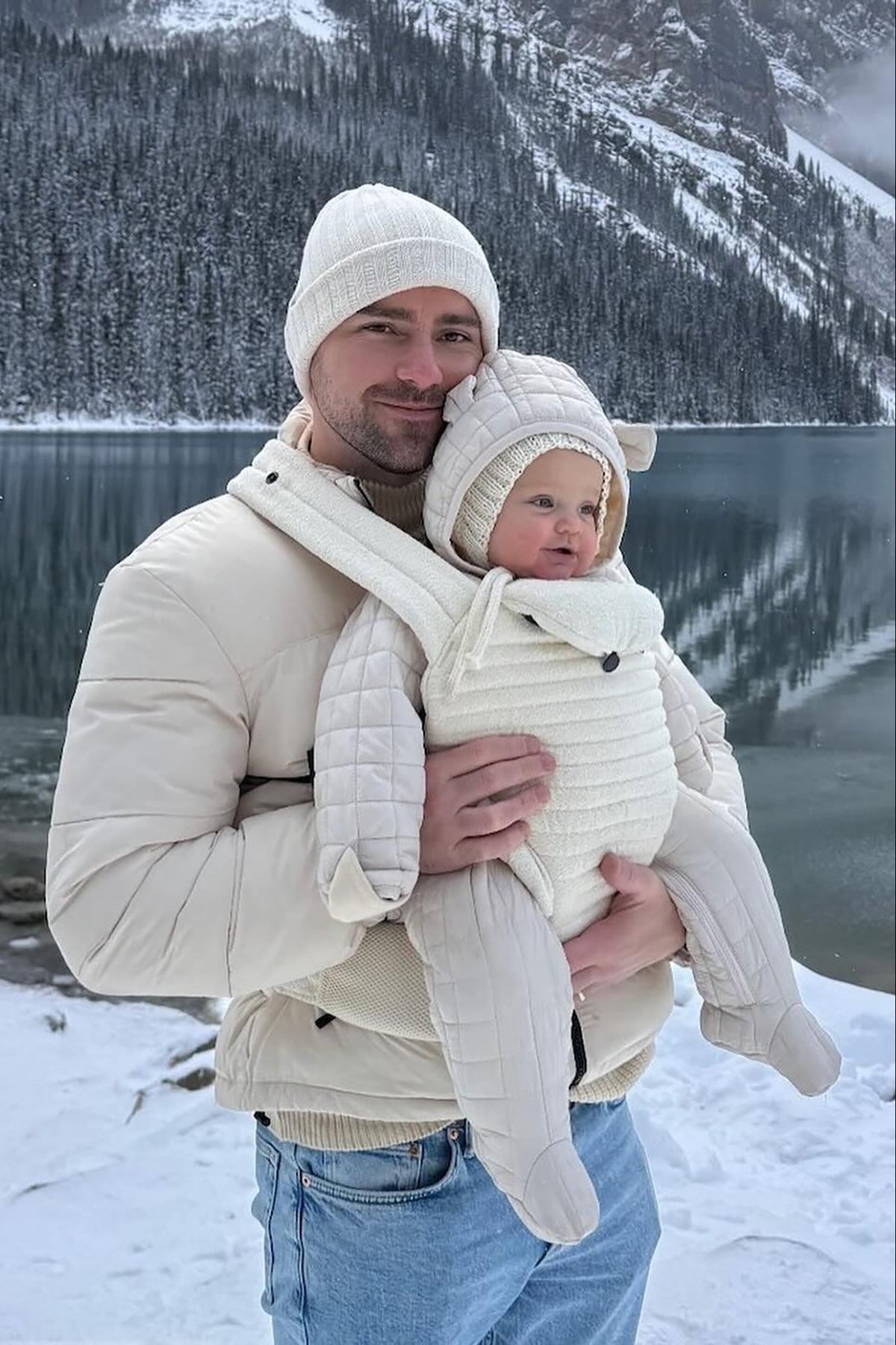 man in the snow wearing the bumpsuit baby career in ivory color