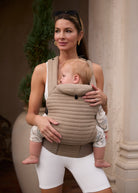 Woman holding a baby in a oyster color baby carrier outdoors