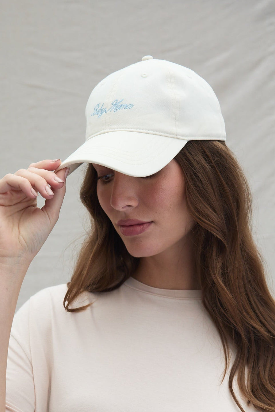 Close-up of the Baby Mama Hat showcasing baby blue embroidered Baby Mama lettering on an ivory cap with a neutral background