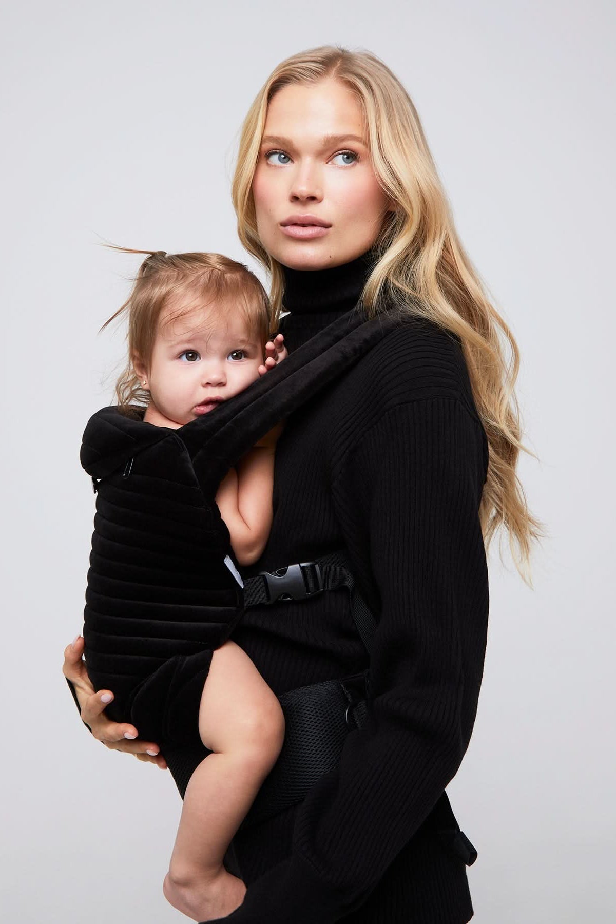lady with baby wearing the bumpsuit armadillo baby carrier in black velvet