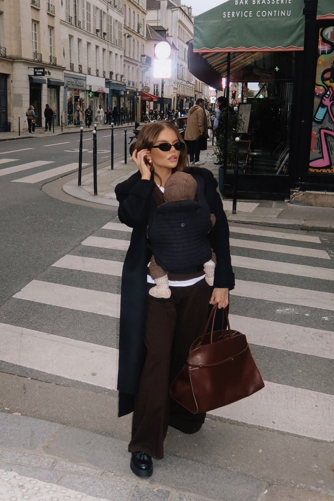 model walking in the streets wearing the armadillo baby carrier in black