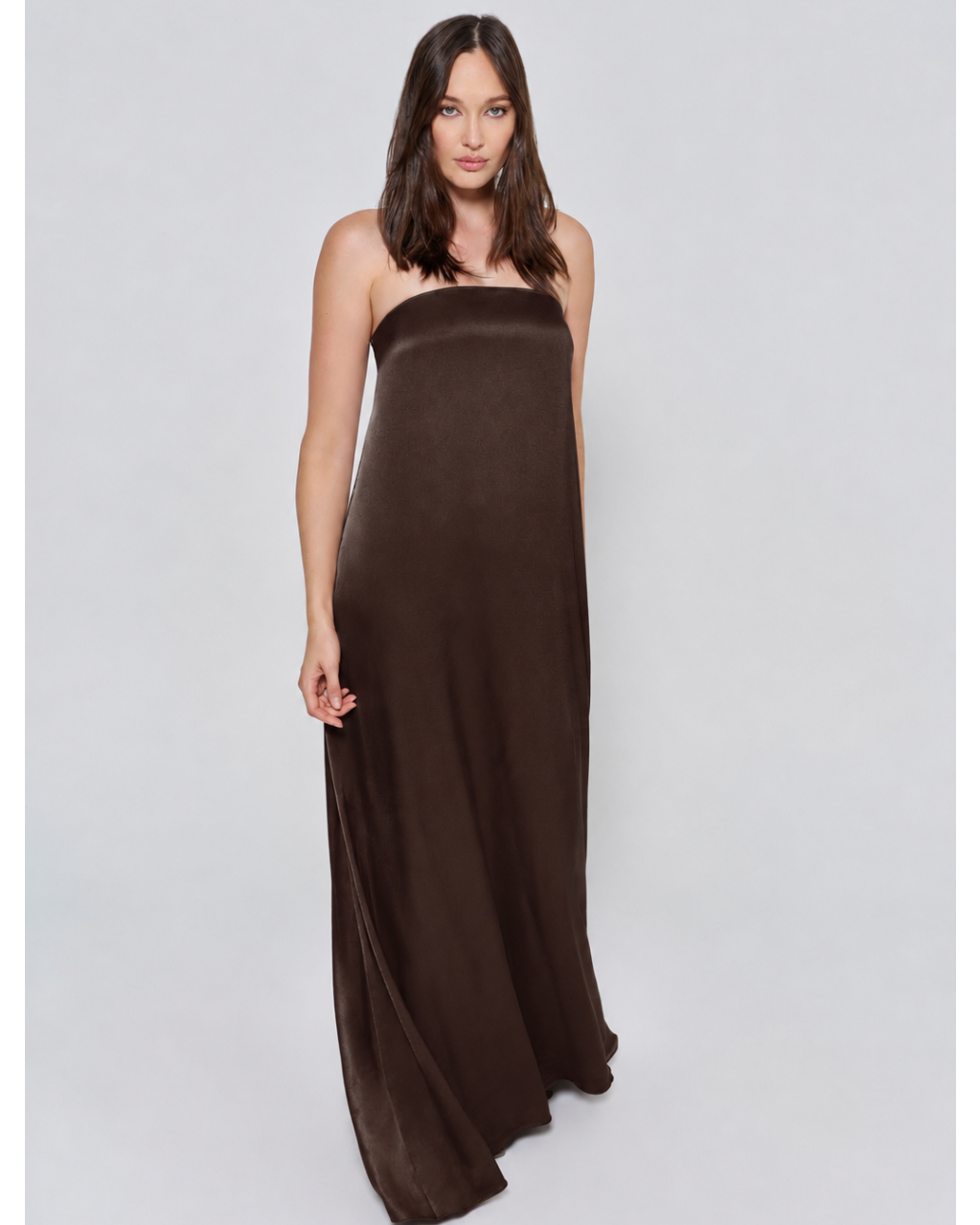 Pregnant woman wearing a Bumpsuit brushed satin gown in a chocolate color against a white background