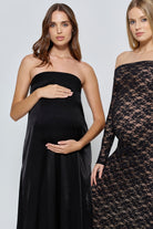 Two women wearing Bumpsuit black dresses, one strapless brushed satin and one lace off the shoulder dress, on a white background.