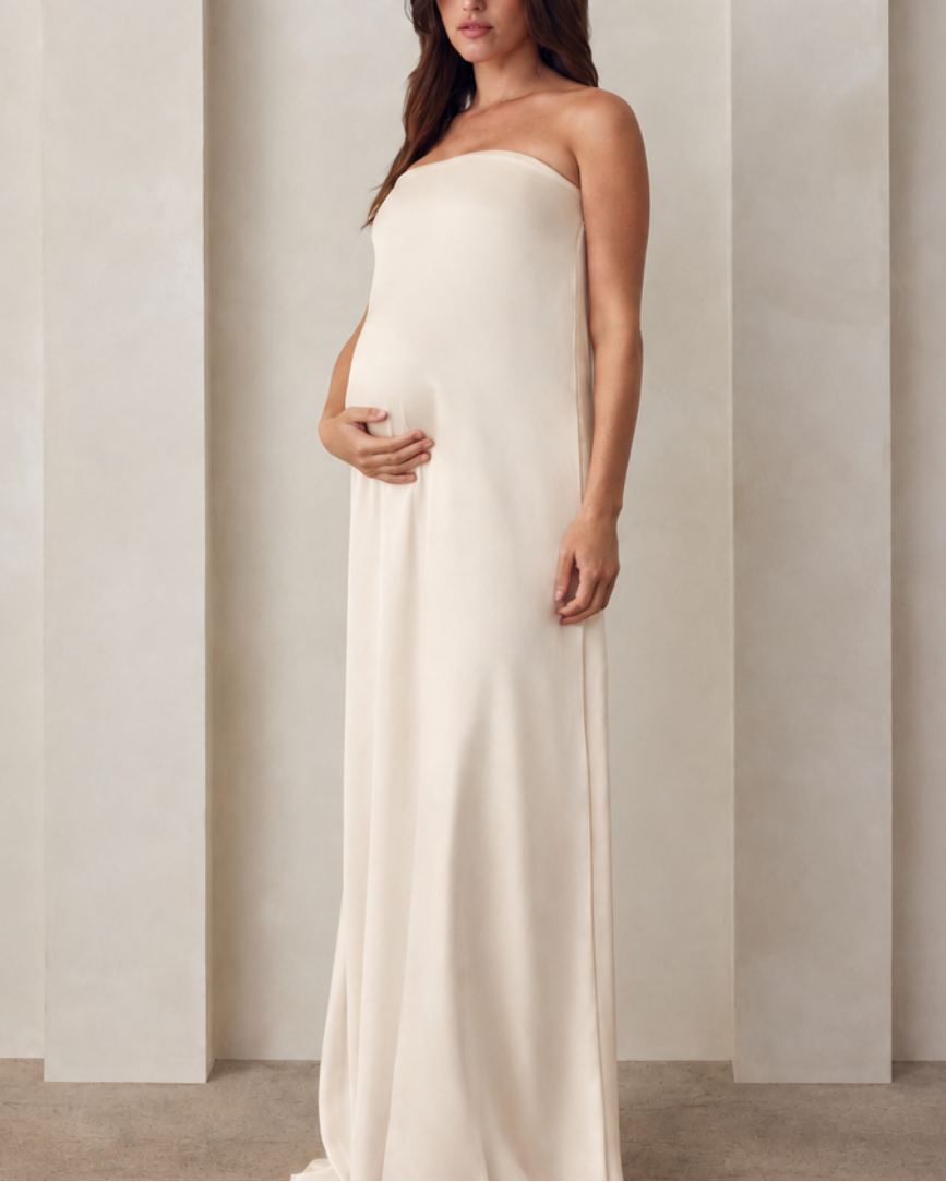 Pregnant woman wearing a Bumpsuit brushed satin gown in champagne color 