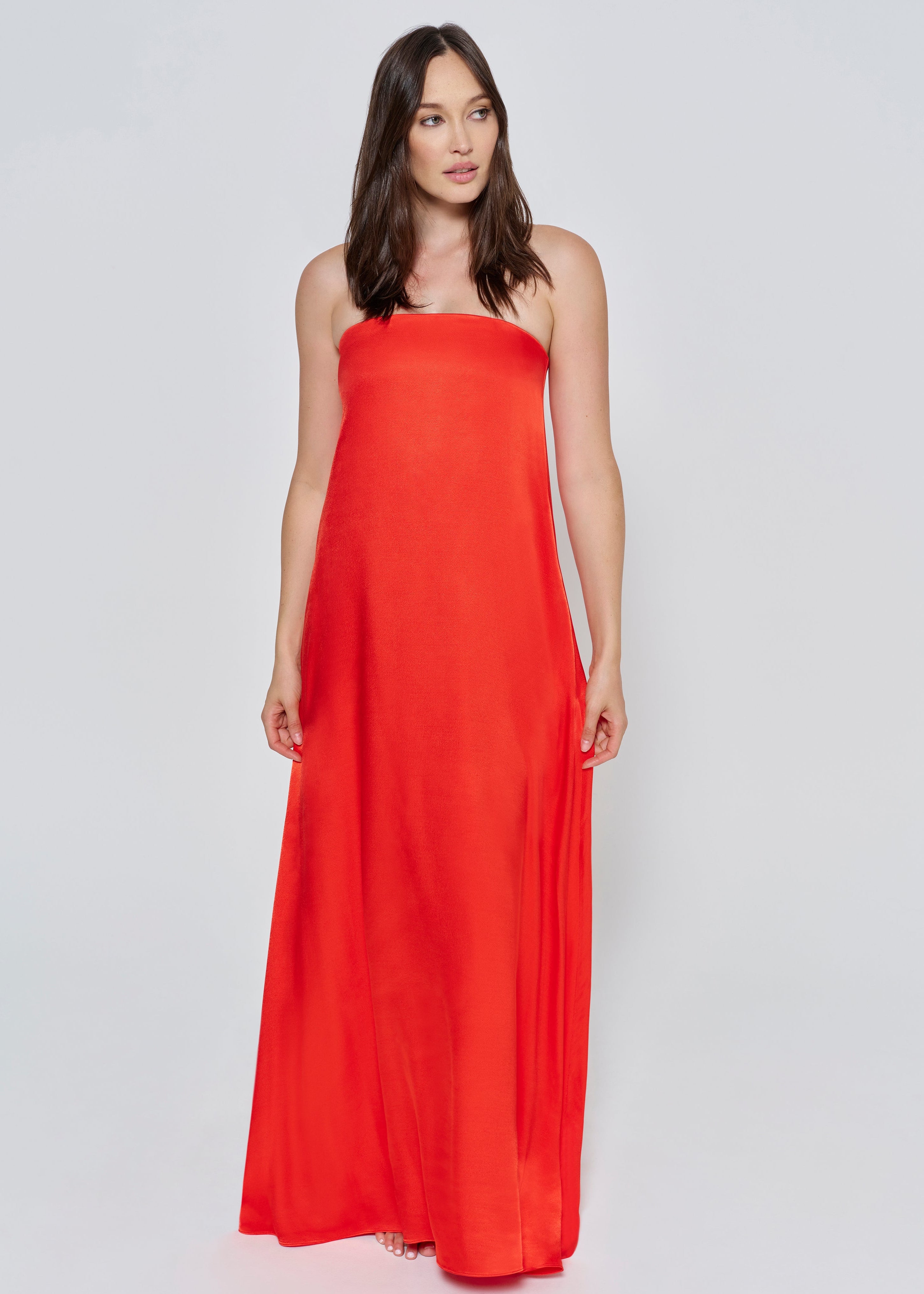 A woman wearing the Bumpsuit brushed satin strapless maxi maternity gown in red against a white background