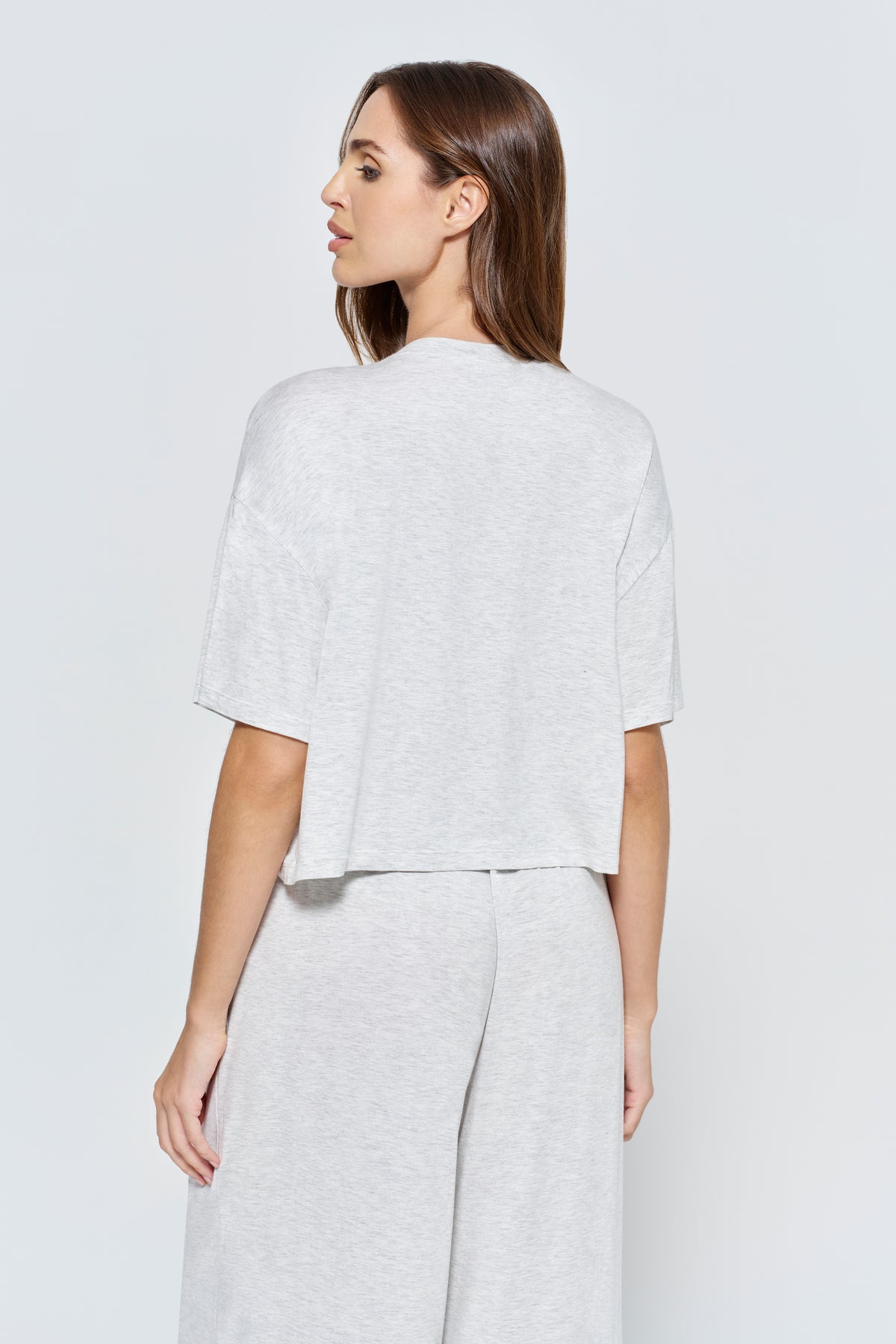 Back view woman wearing Bumpsuit Maternity The Cloud Short Sleeve Crop Tee and pants in a heather grey color