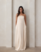 Pregnant woman wearing a Bumpsuit brushed satin gown in champagne color 