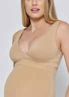 Pregnant woman wearing a beige reversible comfy bra against a plain background