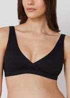 Woman wearing a black reversible comfy bra on a white background