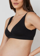 Pregnant woman wearing a black reversible comfy bra in black on a white background