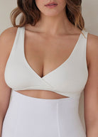 Woman wearing a white reversible comfy bra top and support waist trainer against a plain background