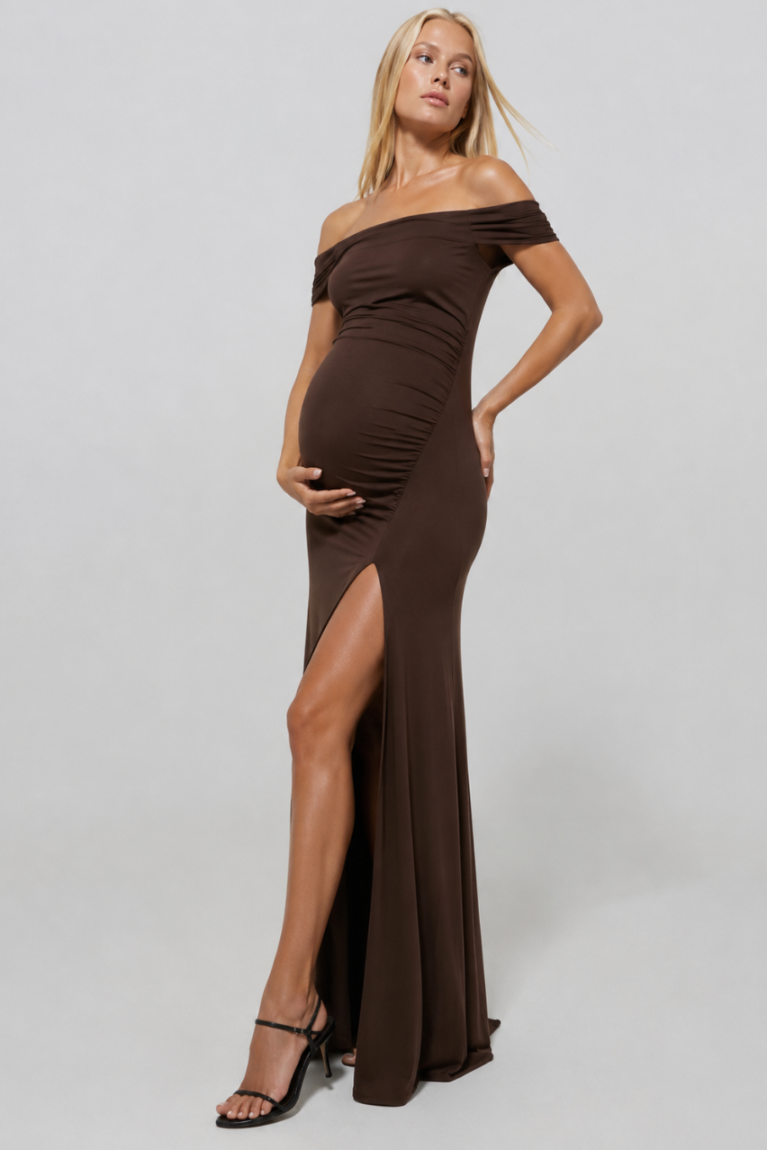 Front view of The Sleeveless Evening Dress on pregnant model with off-shoulder neckline and thigh-high slit on gray backdrop