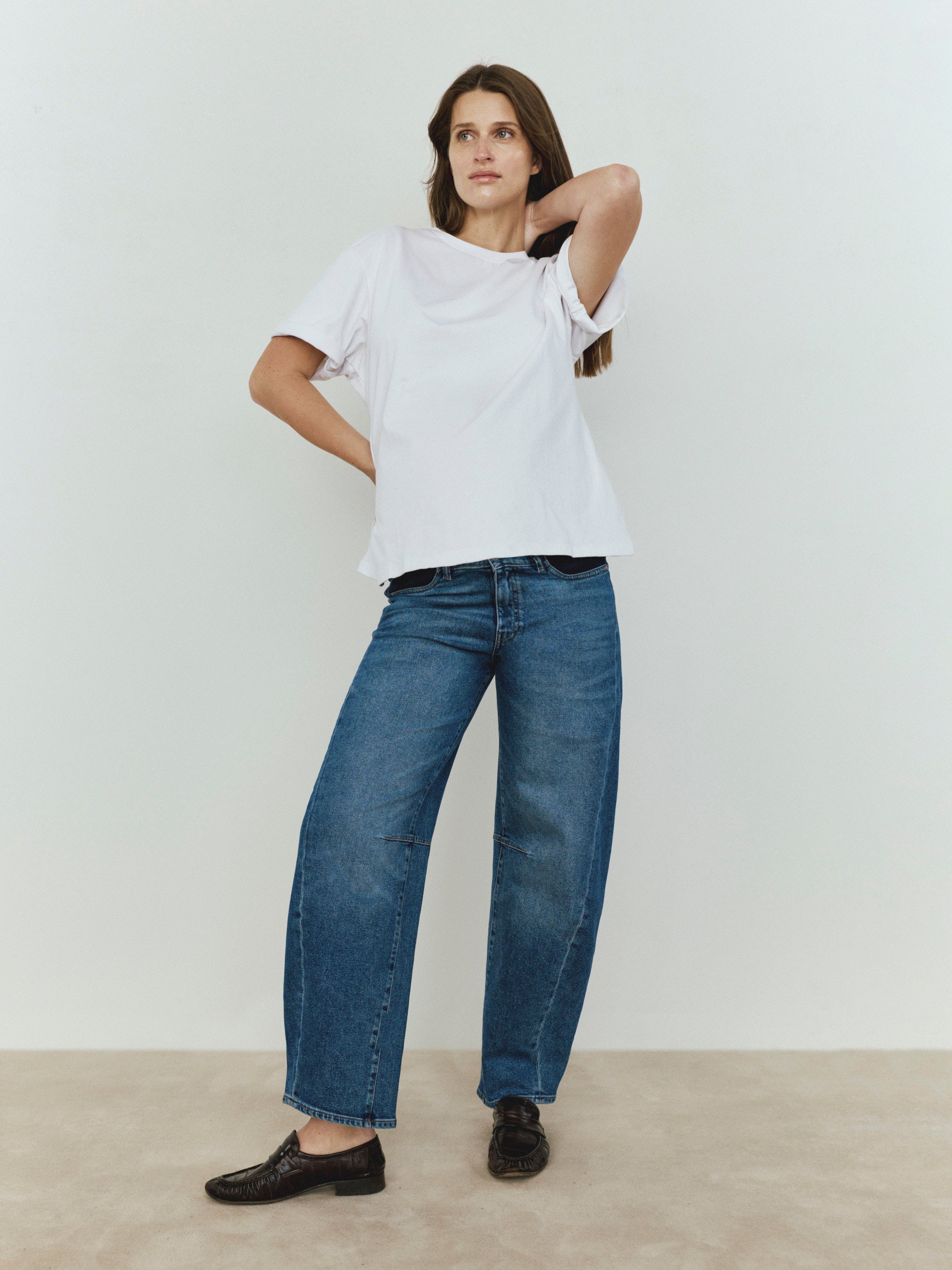 Person wearing a white t-shirt and blue jeans against a plain background