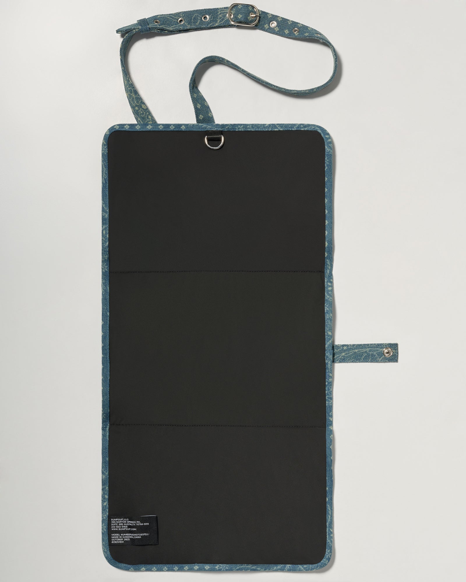 A denim roll up diaper change mat bag by Spell and Bumpsuit,, shown on a light gray background with wipes and diapers