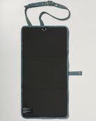 A denim roll up diaper change mat bag by Spell and Bumpsuit,, shown on a light gray background with wipes and diapers