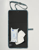 A black denim roll up diaper change mat bag by Spell and Bumpsuit,, shown on a light gray background with wipes and diapers