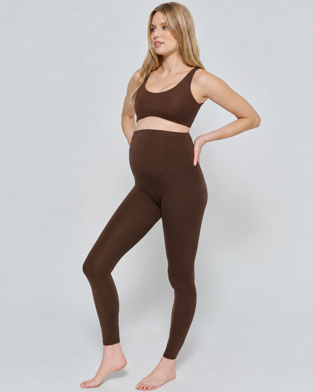 Woman wearing a chocolate brown athletic outfit on a white background