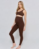 Woman wearing a bumpsuit chocolate brown athletic outfit on a white background