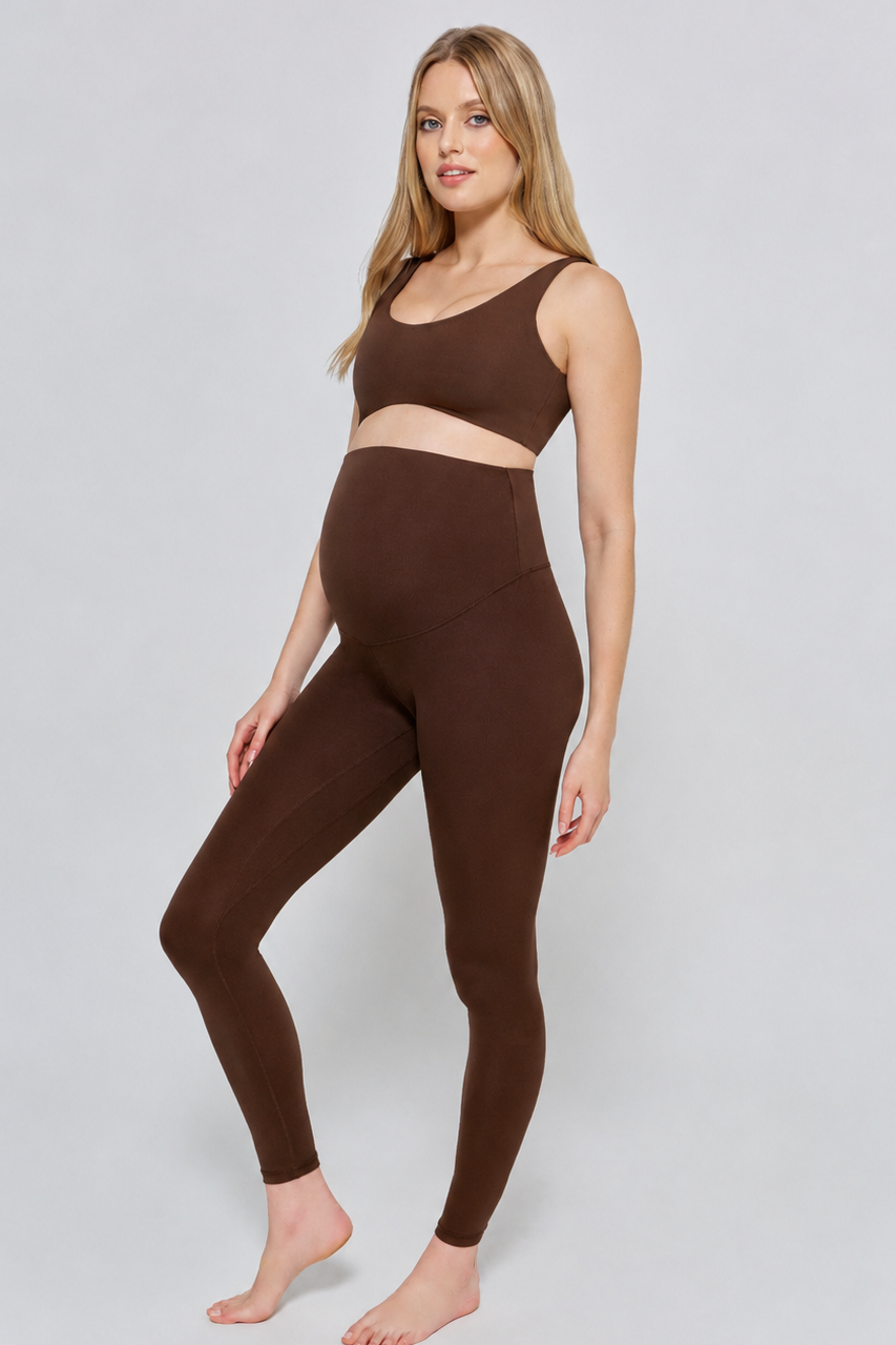 Woman wearing a bumpsuit chocolate brown athletic outfit on a white background
