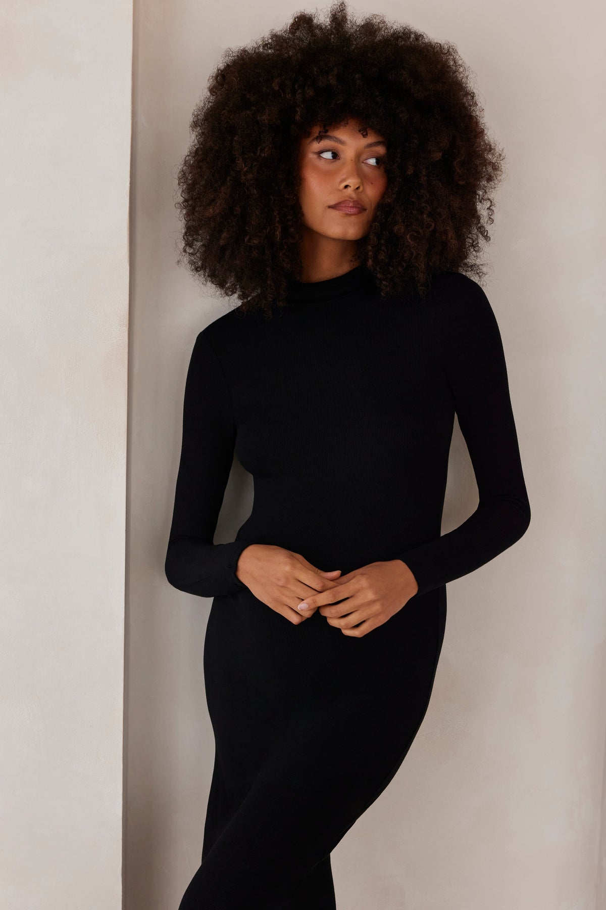 Front view of The Soft Rib Maxi Long Sleeve Dress showcasing black ribbed fabric on a model against a neutral wall