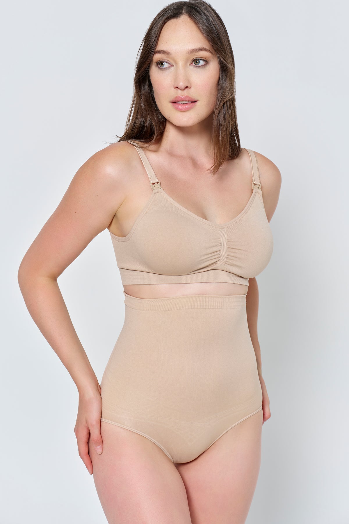 Woman wearing a beige support high waisted brief and support bra set against a plain background