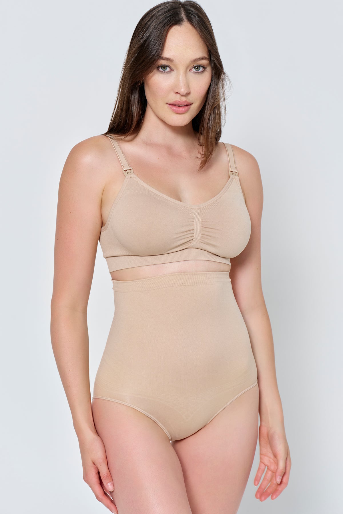 Woman wearing a beige support high waisted brief and support bra set against a plain background