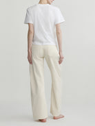 Back view of a person wearing a white t-shirt and beige pants on a plain background