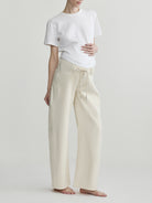 Person wearing a white t-shirt and beige pants on a plain background