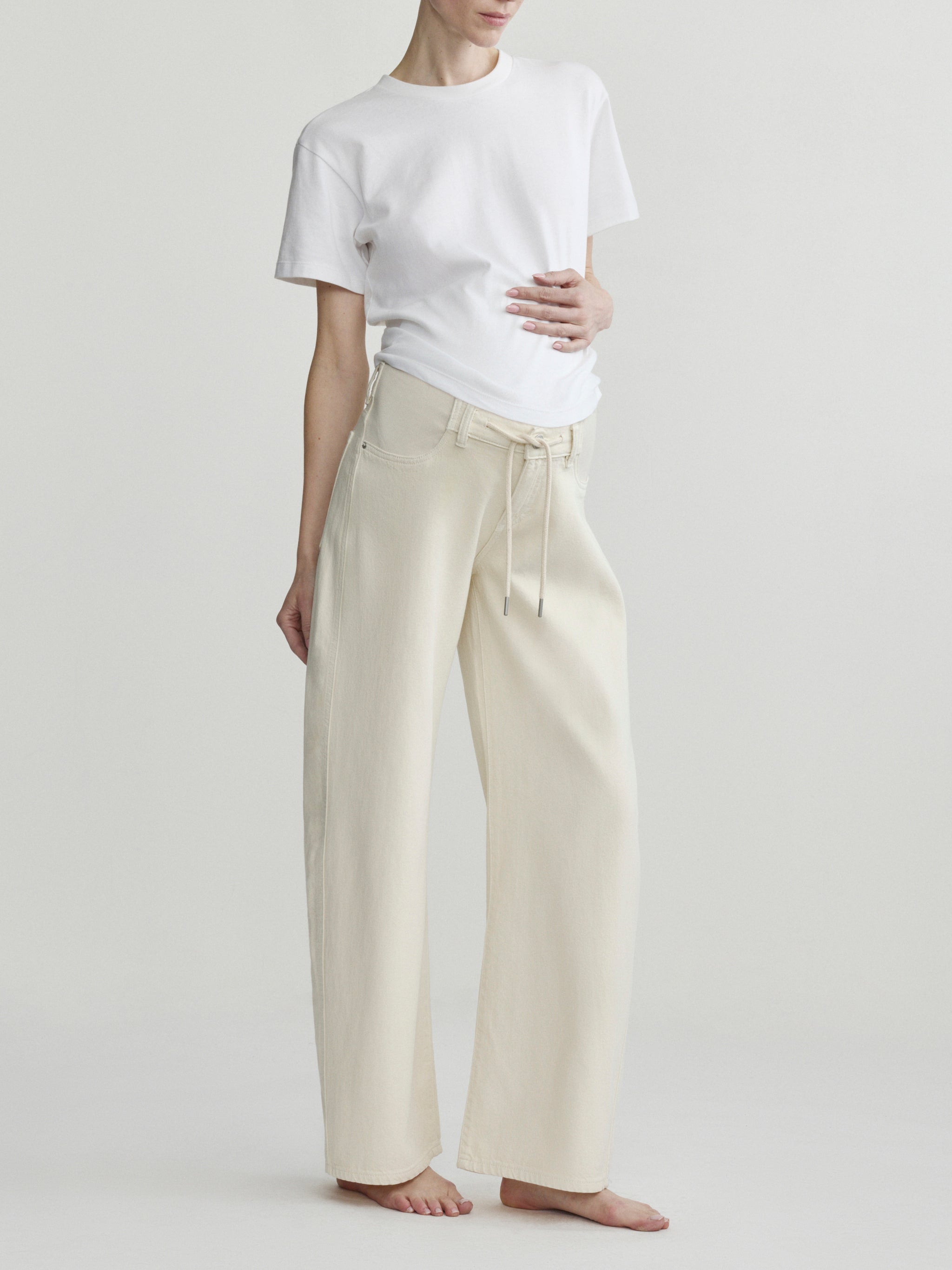 Person wearing a white t-shirt and beige pants on a plain background