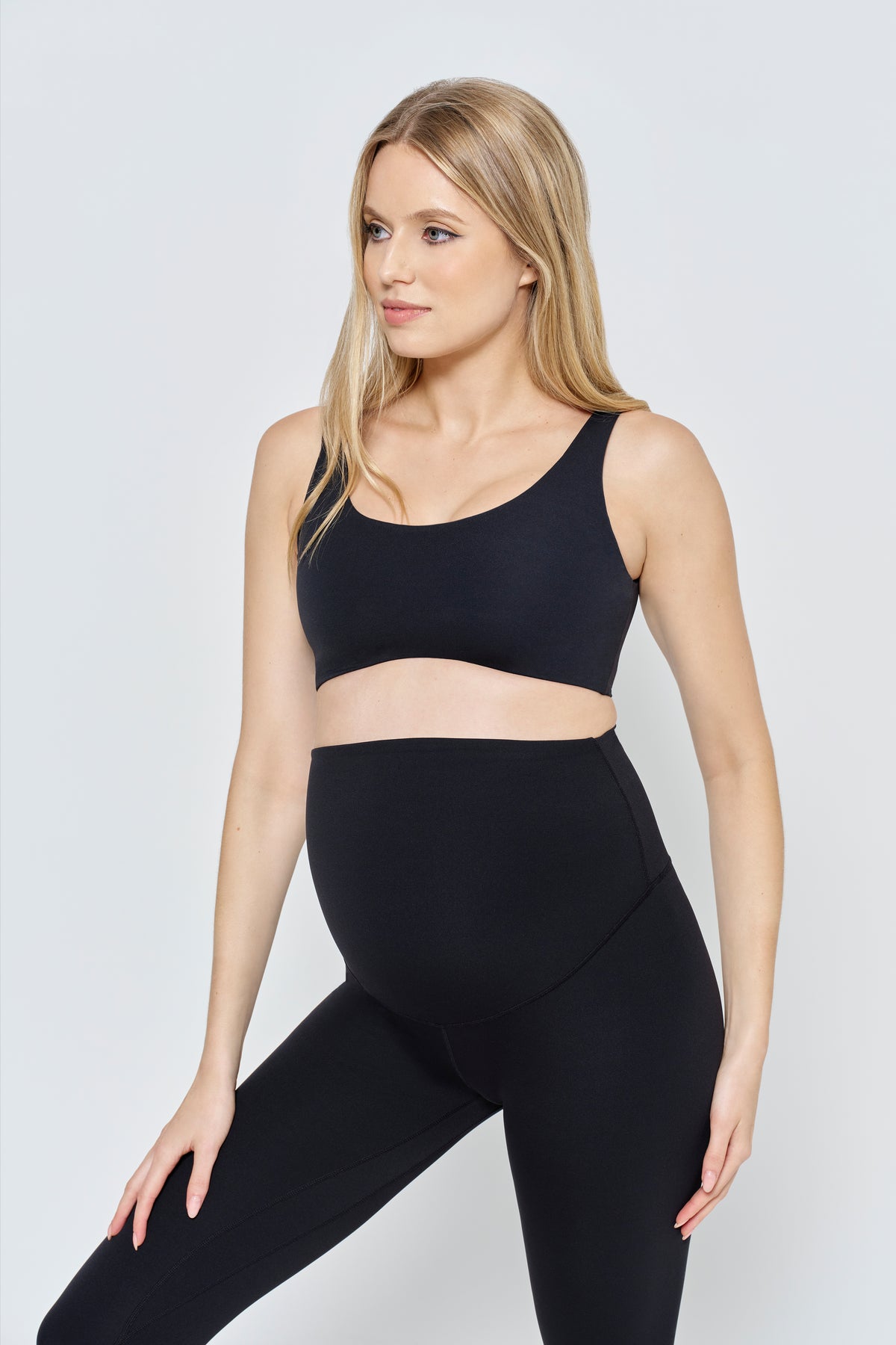 Front close-up of The Perfect Movement Maternity Legging in black showcasing the high waist and curved seams on a model against a light gray background